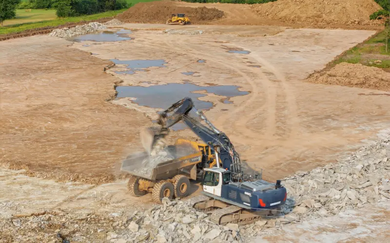 Equipment moving rock during visible site-preparation work at South Coast on July 23, 2026
